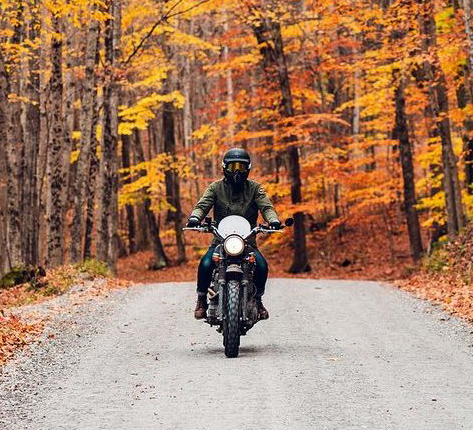 Biker on a motorcycle in the forest during autumn.